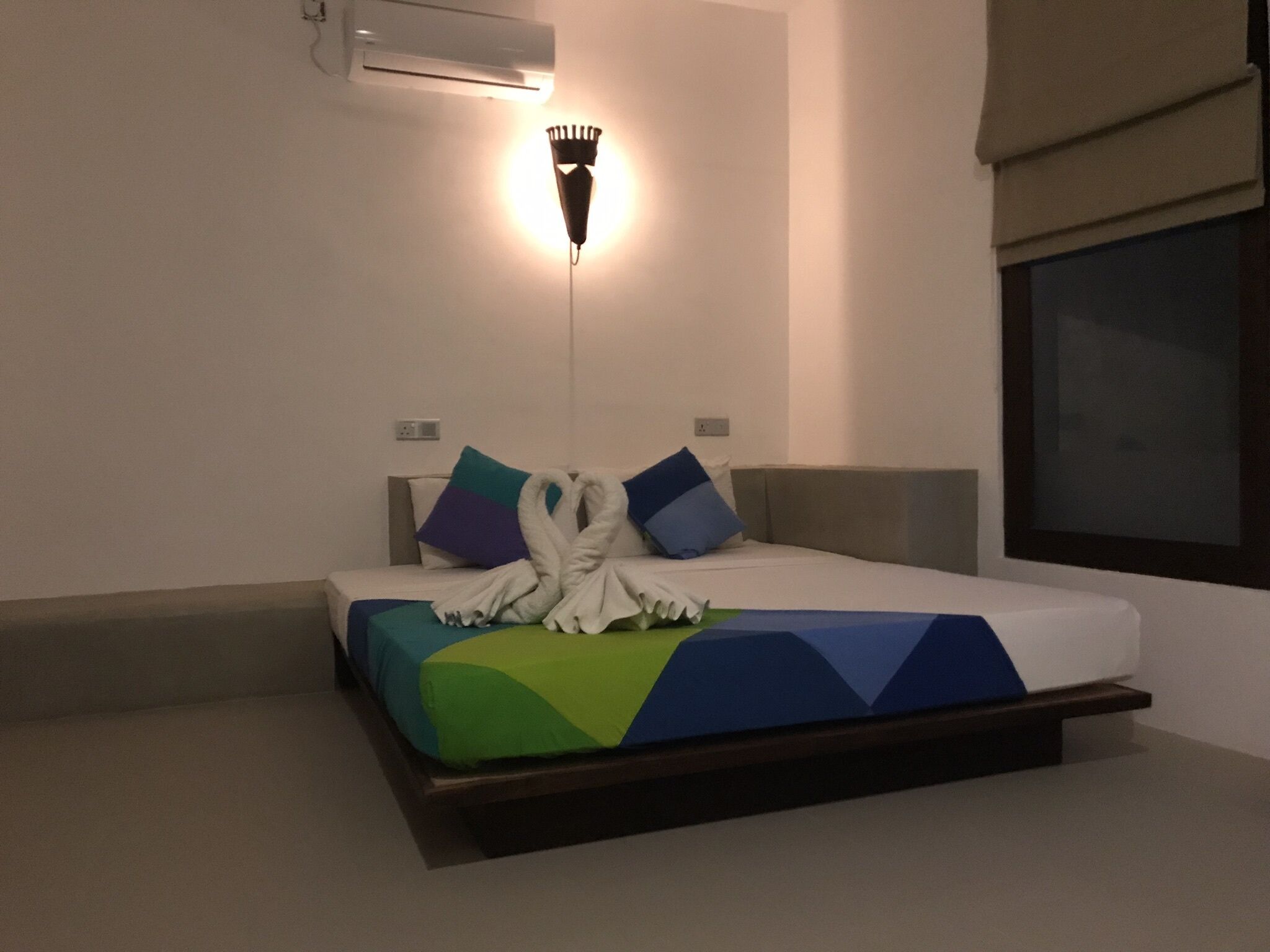 Ein Hotelzimmer mit einem Bett, einer Wandklimaanlage und einer Nachttischlampe.