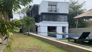 A modern two-story building with a swimming pool and lounge chairs. - Handagedara Resort (Mirissa)