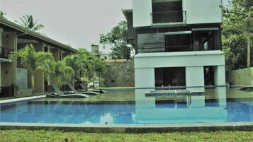 Una piscina al aire libre, sombrillas, sillones reclinables de piscina