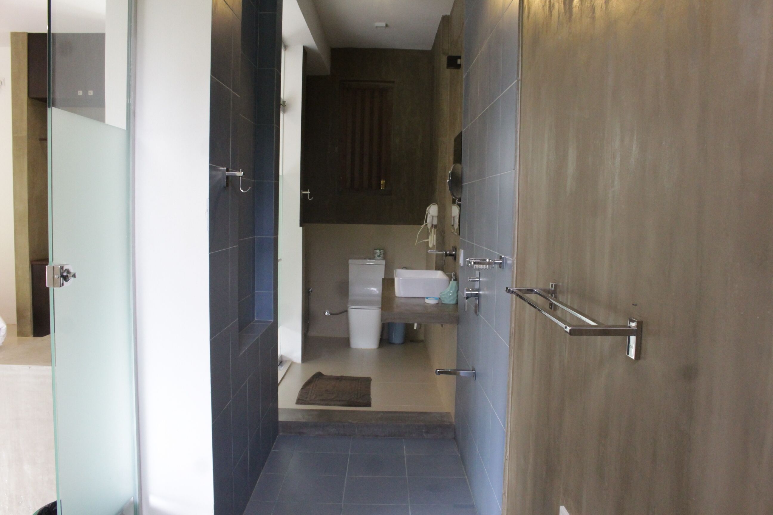 A modern bathroom with a glass shower door, a toilet, a sink, and a mirror.