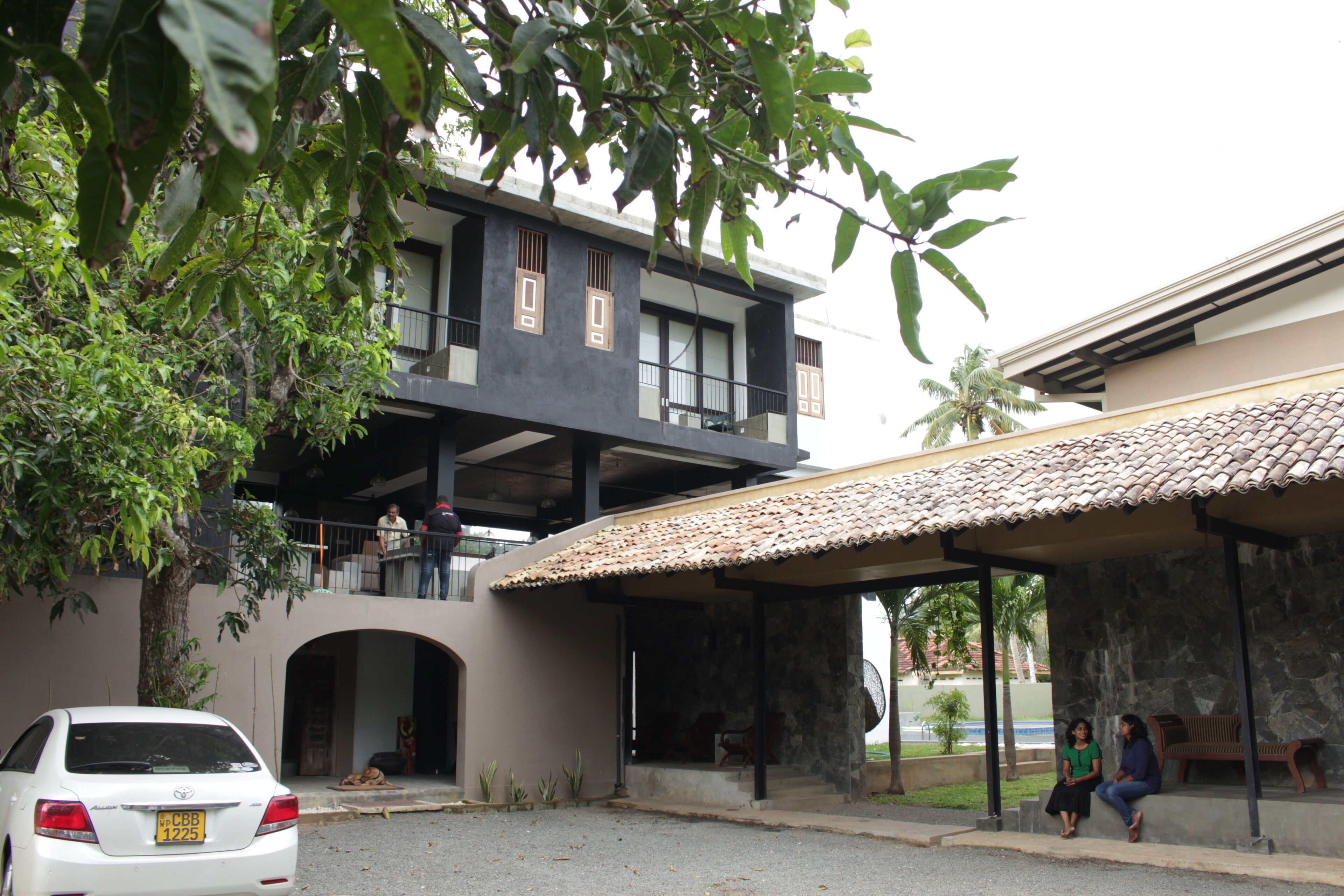 A two-story building with a balcony, a covered outdoor seating area, and a car parked in front.