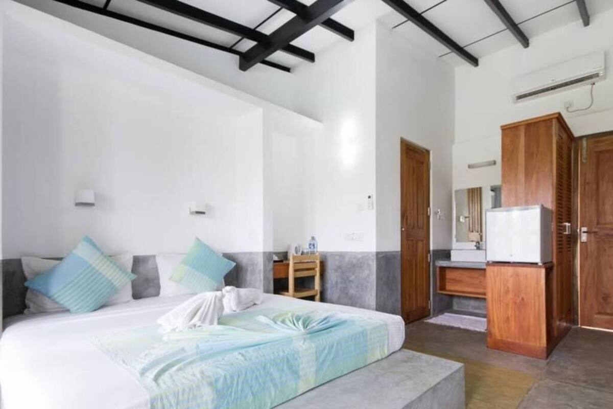 A bedroom with a bed, bedside tables, a wardrobe, and a bathroom with a mirror and sink.