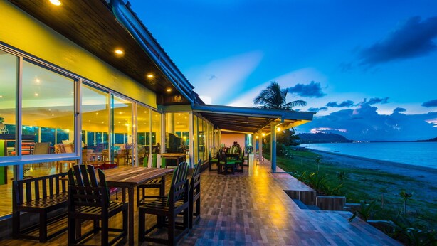 A modern building with a wooden deck and glass walls overlooking a beach. - Starlight Beach Resort Chumphon (Chumphon)
