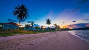 A beach with a row of houses and palm trees. - Starlight Beach Resort Chumphon (Chumphon)