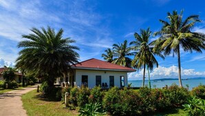 A beachfront property with a red-roofed building, palm trees, and a clear view of the ocean. - Starlight Beach Resort Chumphon (Chumphon)