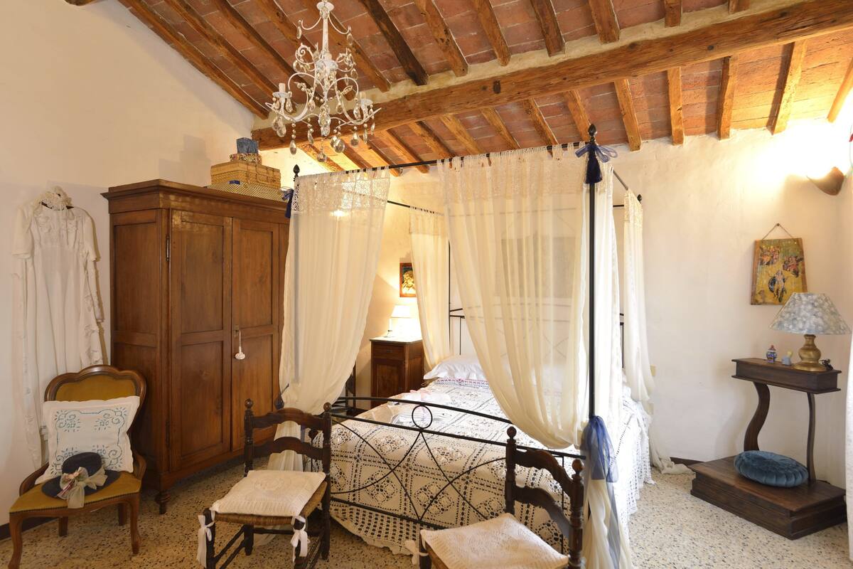 Un dormitorio con cama con dosel, muebles de madera y una araña.