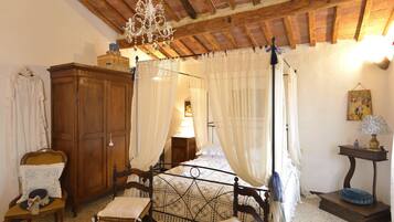 Un dormitorio con cama con dosel, muebles de madera y una araña.
