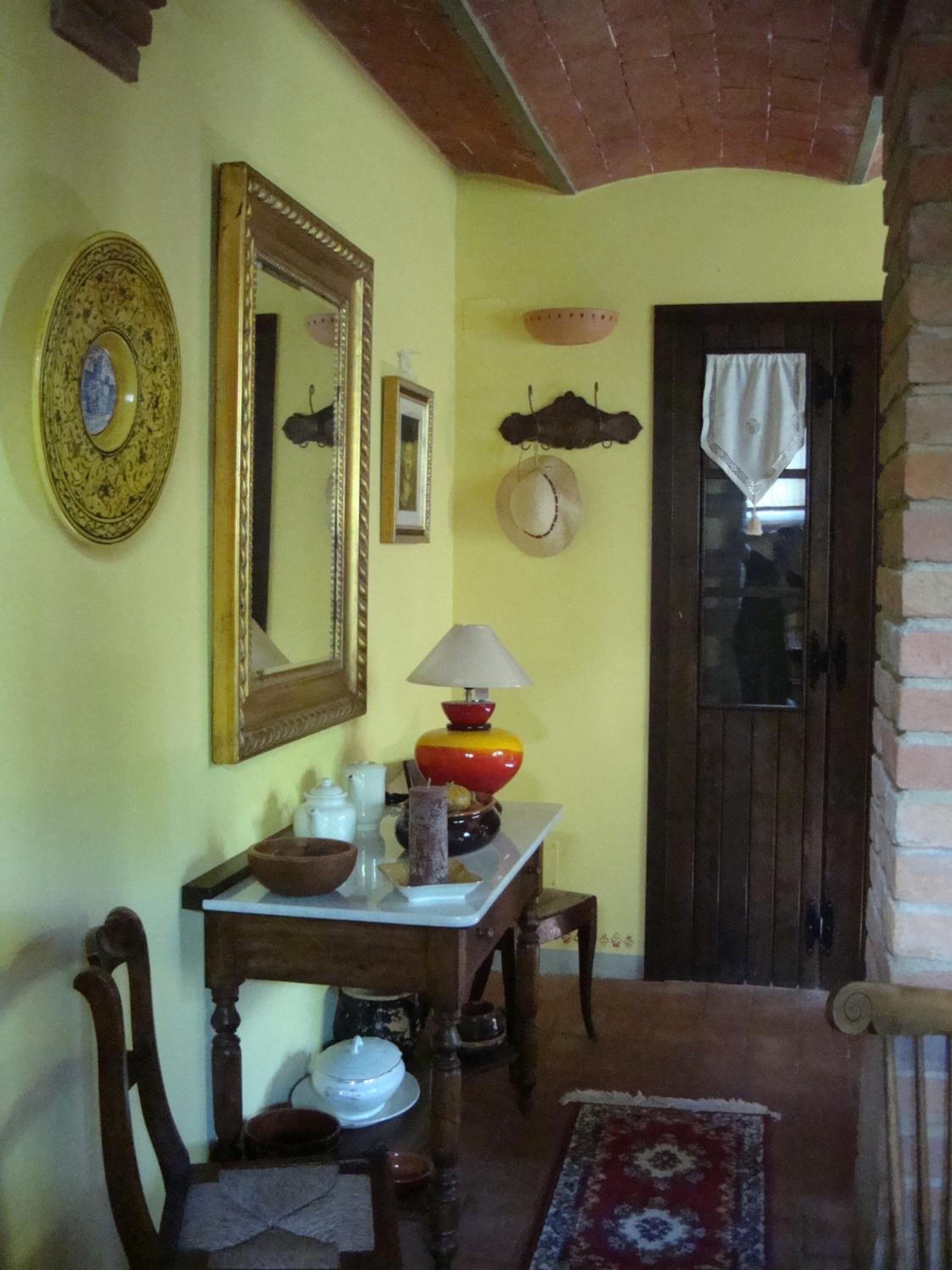 Una habitación con una mesa de madera, sillas, un espejo y una puerta.