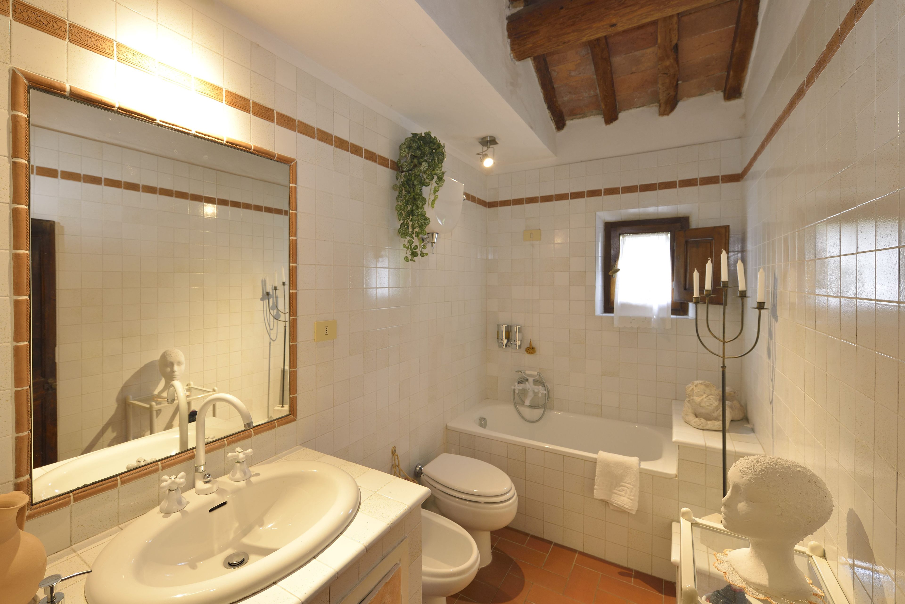 Un baño con un espejo grande, un lavabo, un inodoro y una bañera.