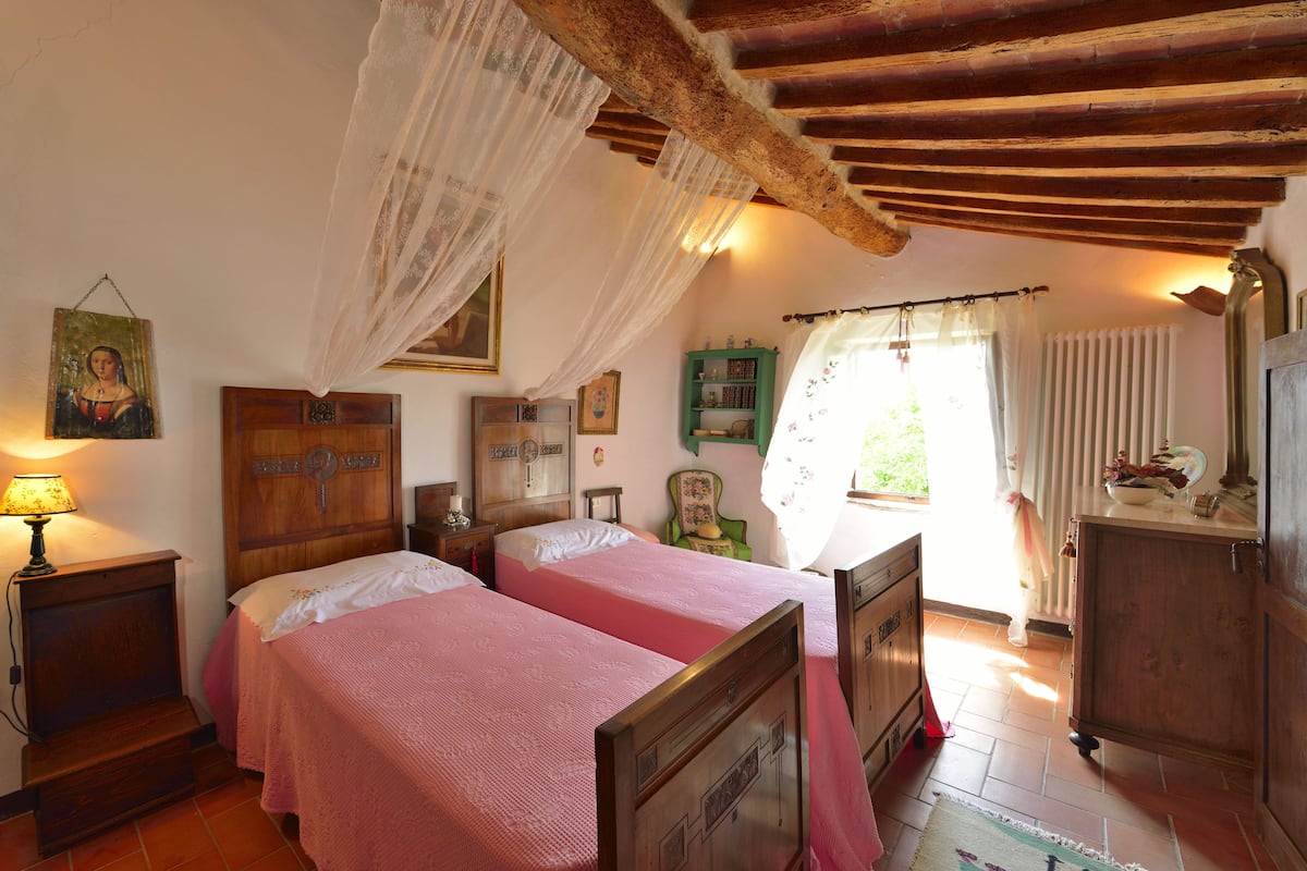 Un dormitorio con dos camas, muebles de madera, una ventana con cortinas y un cuadro en la pared.