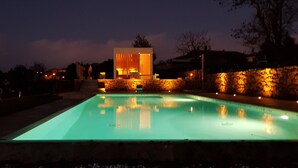 A swimming pool with a modern house in the background, stone walls, and a stone pathway leading to the pool. - La Murata (Rapolano Terme)