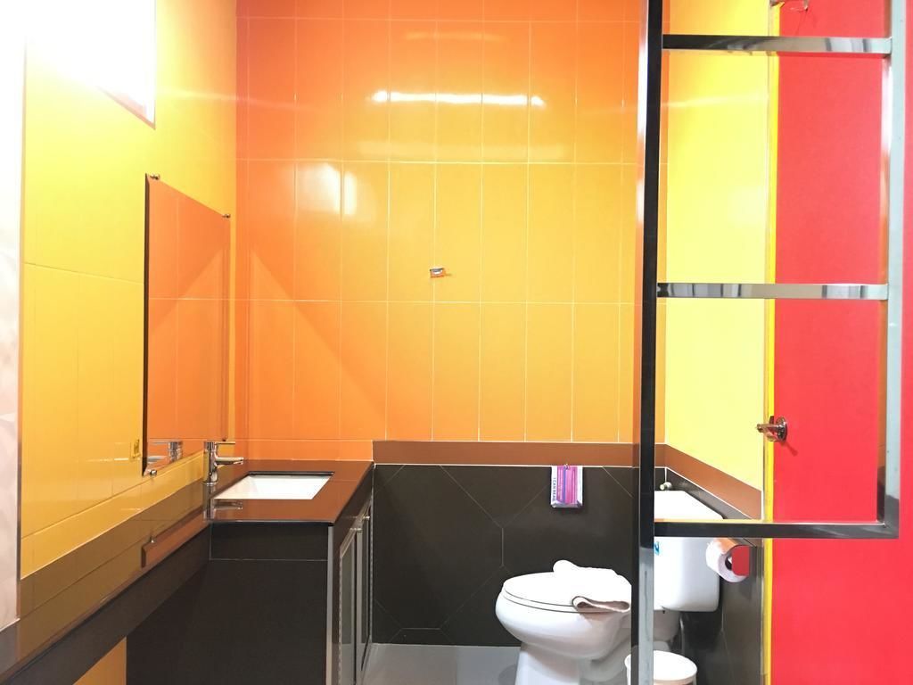 A bathroom with a black sink, white toilet, and orange walls.