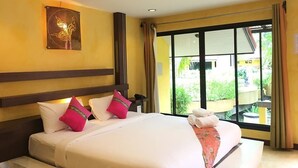 Habitación de hotel con una cama grande, una mesita de noche, una lámpara de pared y vistas al exterior a través de un ventanal corredero.