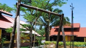 Un columpio de madera en un área verde, con un edificio al fondo.