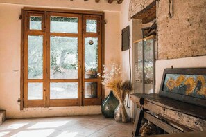 A room with a large wooden door, a rustic wooden bench, and a vase with dried plants. - Agriturismo La Torretta (Siena)