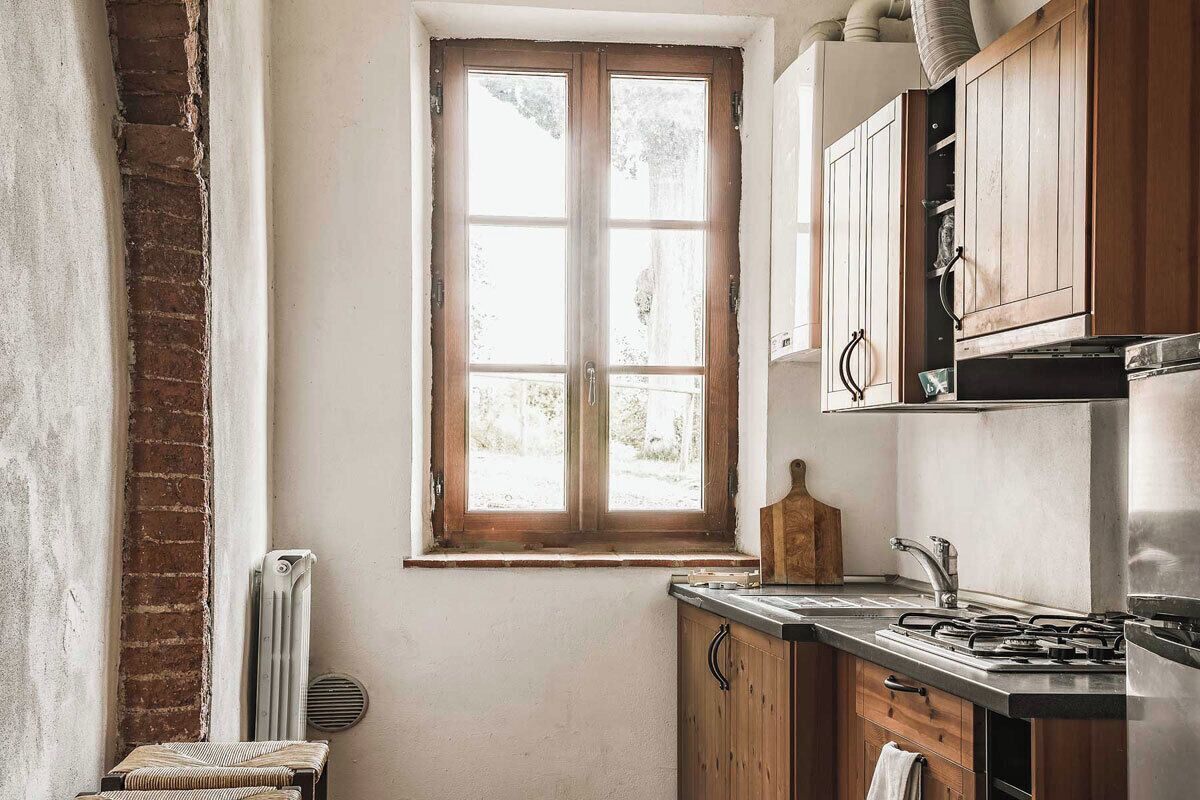 Una cocina con ventana, armarios de madera, encimera y estufa.