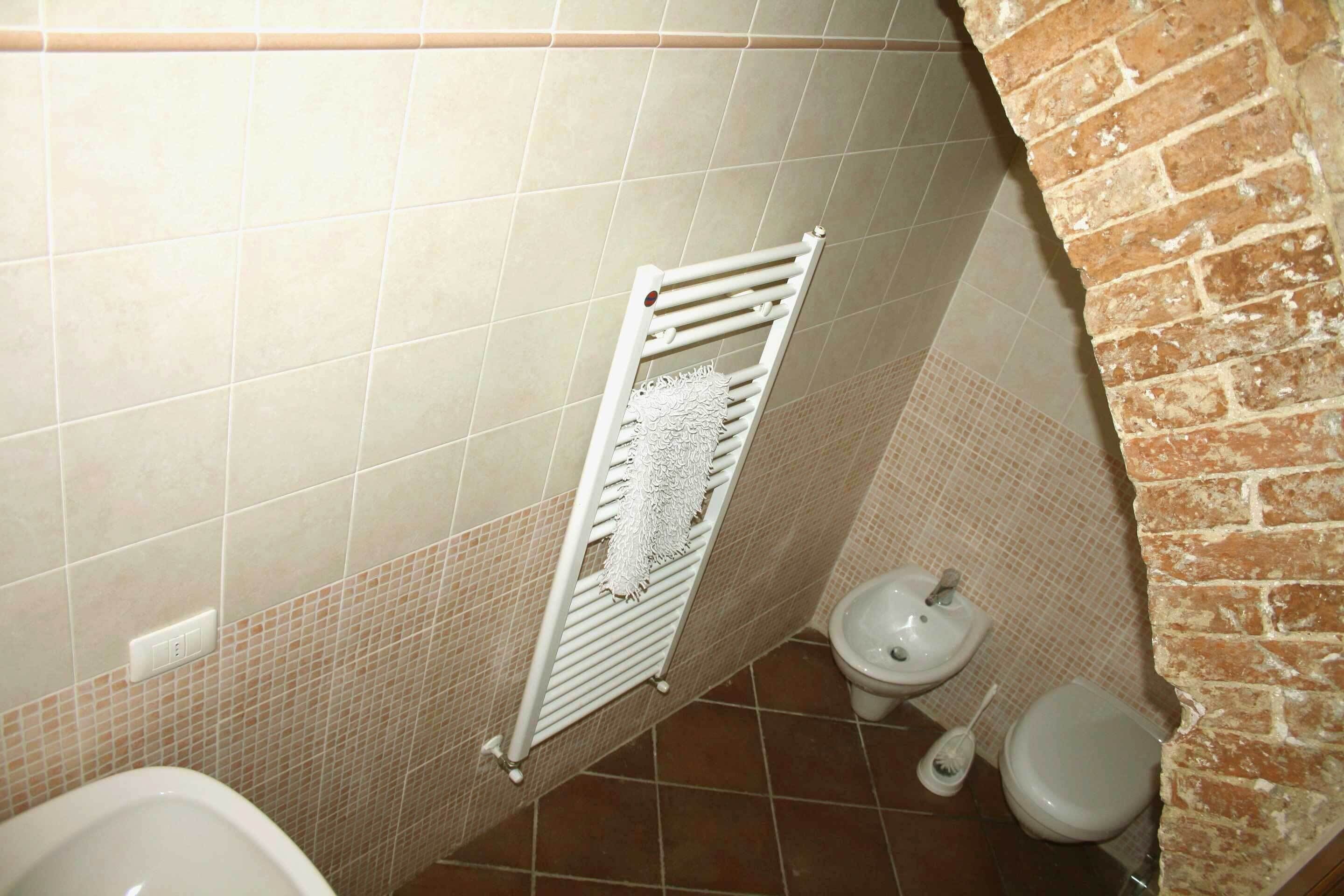 Une salle de bain avec un radiateur blanc, des toilettes et un bidet.