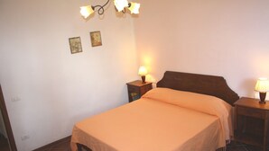 A bedroom with a single bed, two bedside tables with lamps, and two wall-mounted picture frames. - Agriturismo La Torretta (Siena)