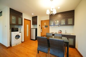 A compact kitchen with a dining area, a washing machine, and a refrigerator. - S17 @ Nimman Hotel (Chiang Mai)