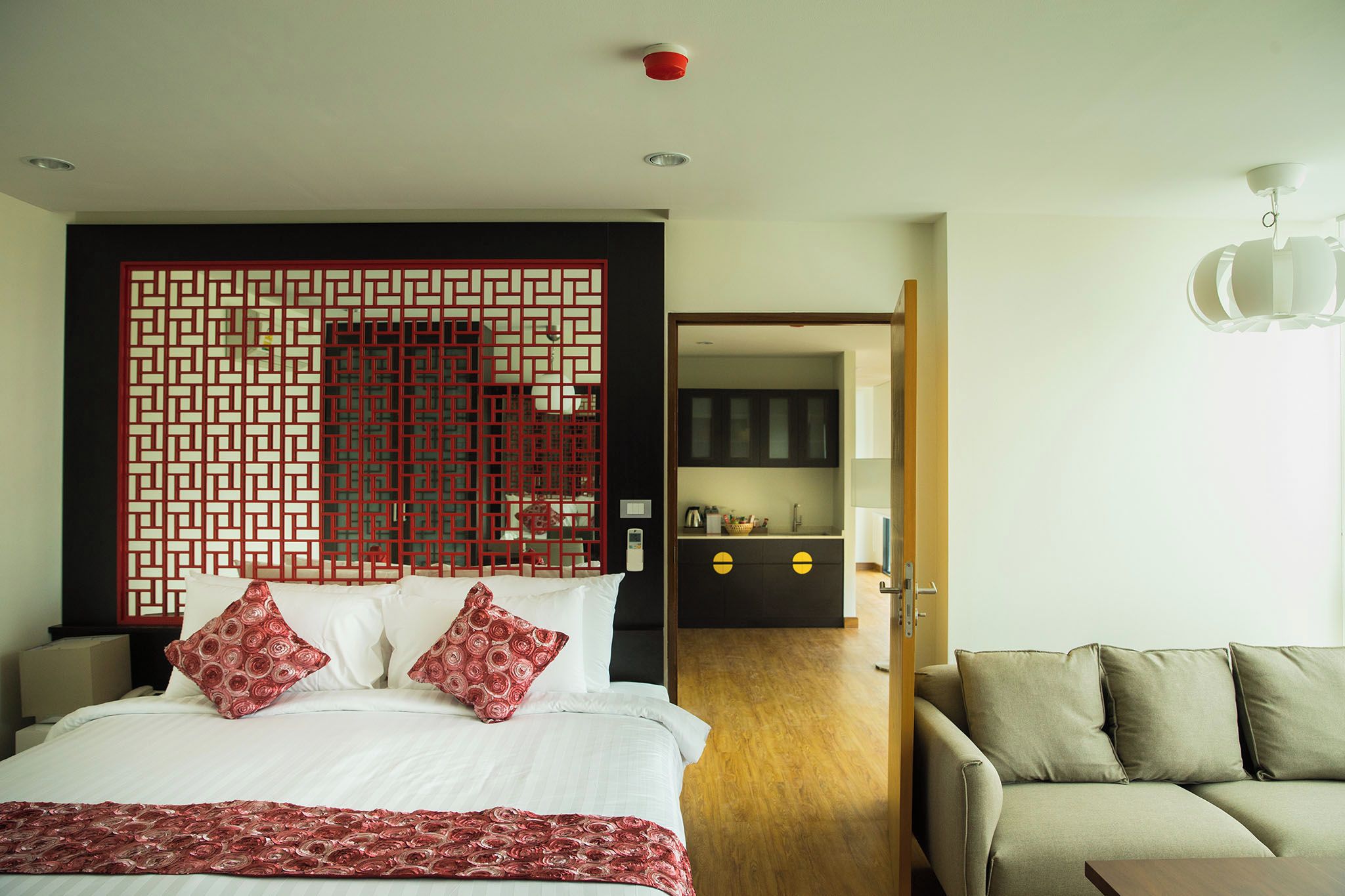 Une chambre d’hôtel comprenant un lit, un canapé, un coin cuisine et un paravent décoratif.