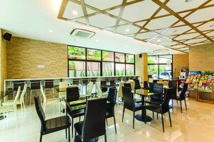 Una cafetería moderna con pared de ladrillo, ventanas amplias y diversas opciones de asiento, incluidas mesas y sillas.