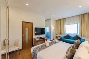 A hotel room with a bed, a desk with a television, a sofa, and a window with curtains. - S17 @ Nimman Hotel (Chiang Mai)