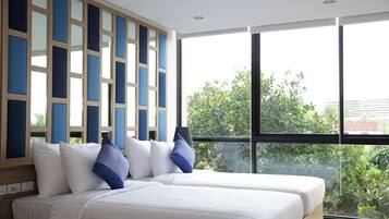 Habitación de hotel con dos camas, un ventanal grande y vistas a zonas verdes.