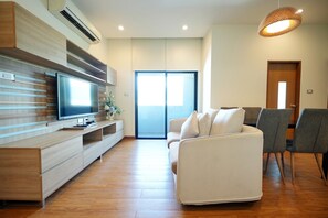 A modern living room with a flat-screen TV, wooden entertainment unit, and a sofa. - S17 @ Nimman Hotel (Chiang Mai)