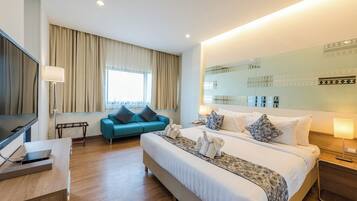 Una habitación de hotel con cama, sofá, televisión y escritorio.