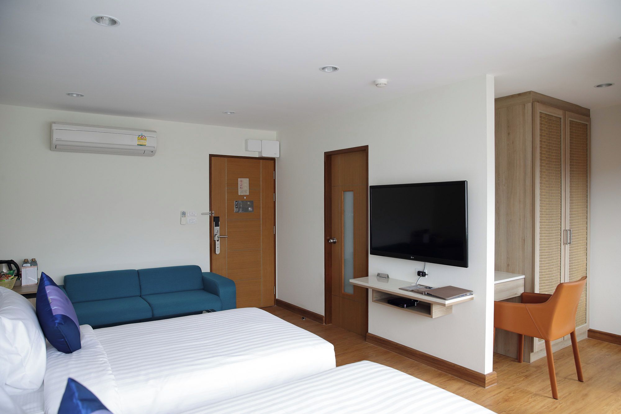 Una habitación de hotel con una cama, un sofá azul, un televisor y un escritorio con una silla.