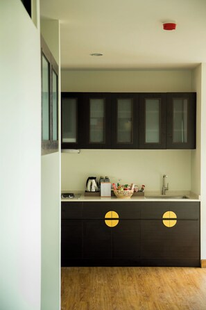 A modern kitchen with dark cabinetry, a stainless steel sink, and a wooden floor. - S17 @ Nimman Hotel (Chiang Mai)