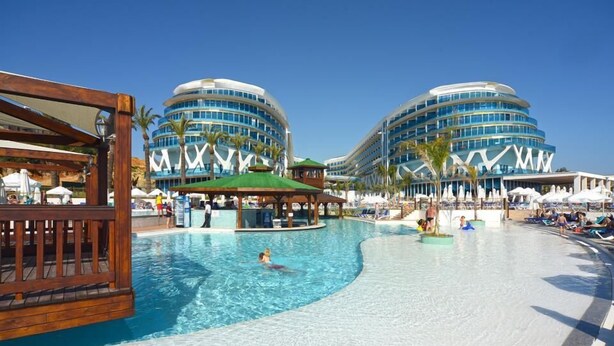 A swimming pool area with a wooden deck, lounge chairs, and umbrellas. - Vikingen Infinity Resort & Spa - All Inclusive (Alanya)