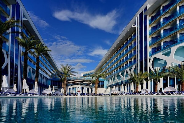 A modern hotel with a pool, multiple floors, and palm trees. - Vikingen Infinity Resort & Spa - All Inclusive (Alanya)