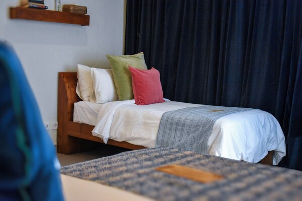 A bed with a wooden frame, white bedding, and multiple pillows.