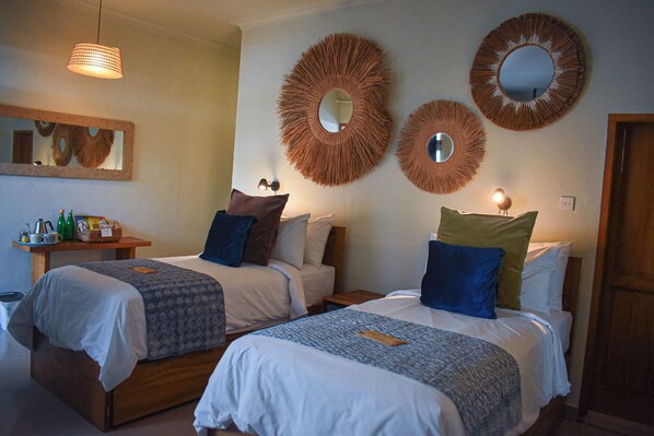 Habitación de hotel con dos camas, una mesita de noche, un espejo y un espejo circular fijado a la pared.