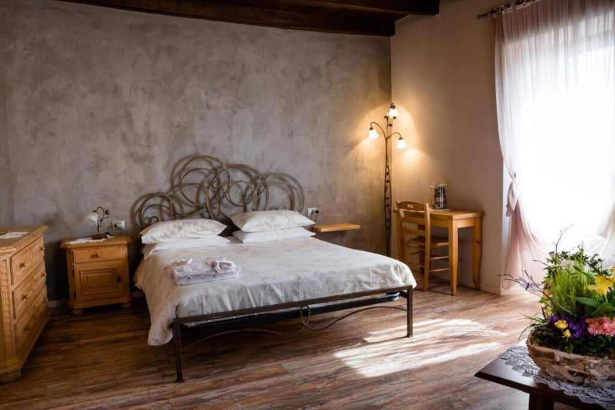 A bedroom with a metal bed frame, wooden nightstands, a bedside table, and a floor lamp.