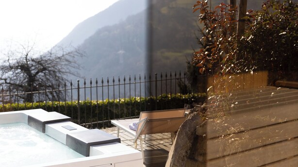 A hot tub with a mountain view, a wooden bench, and a stone pathway.