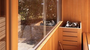 A wooden sauna with a large window, a wooden bench, and a bucket.