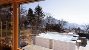 A hot tub in a well-maintained outdoor area with a view of mountains and trees.