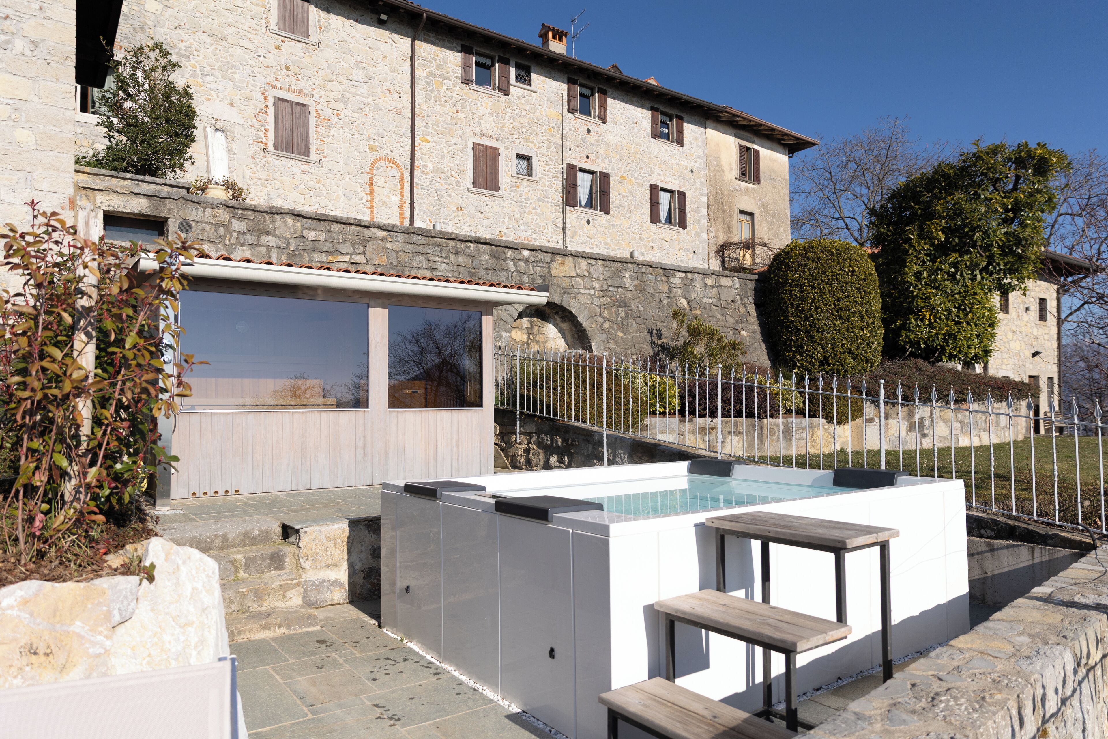 Un edificio de piedra con piscina, mobiliario exterior y una escalera de piedra.