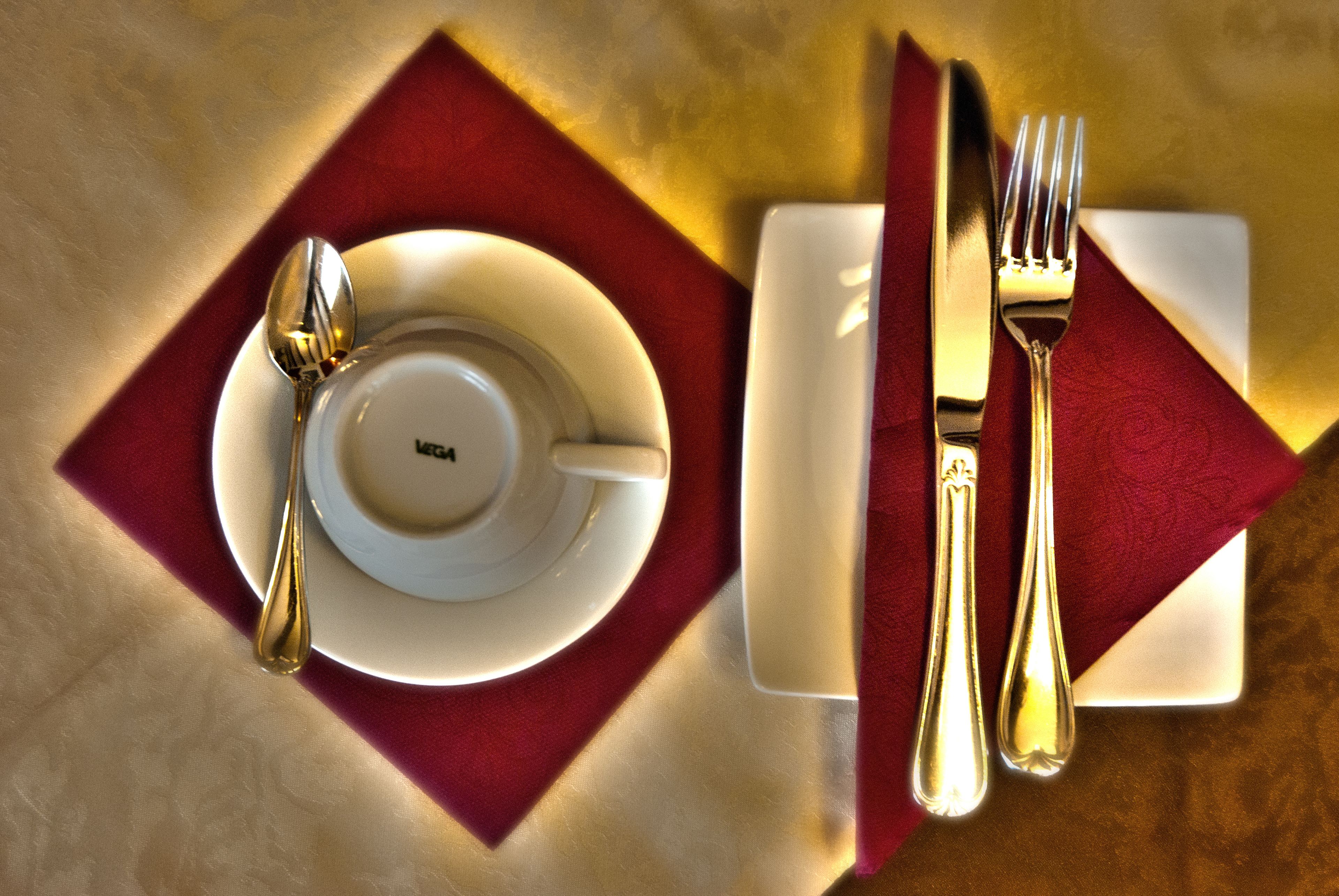 A table set with a white plate, a spoon, a fork, and a knife on a red napkin.