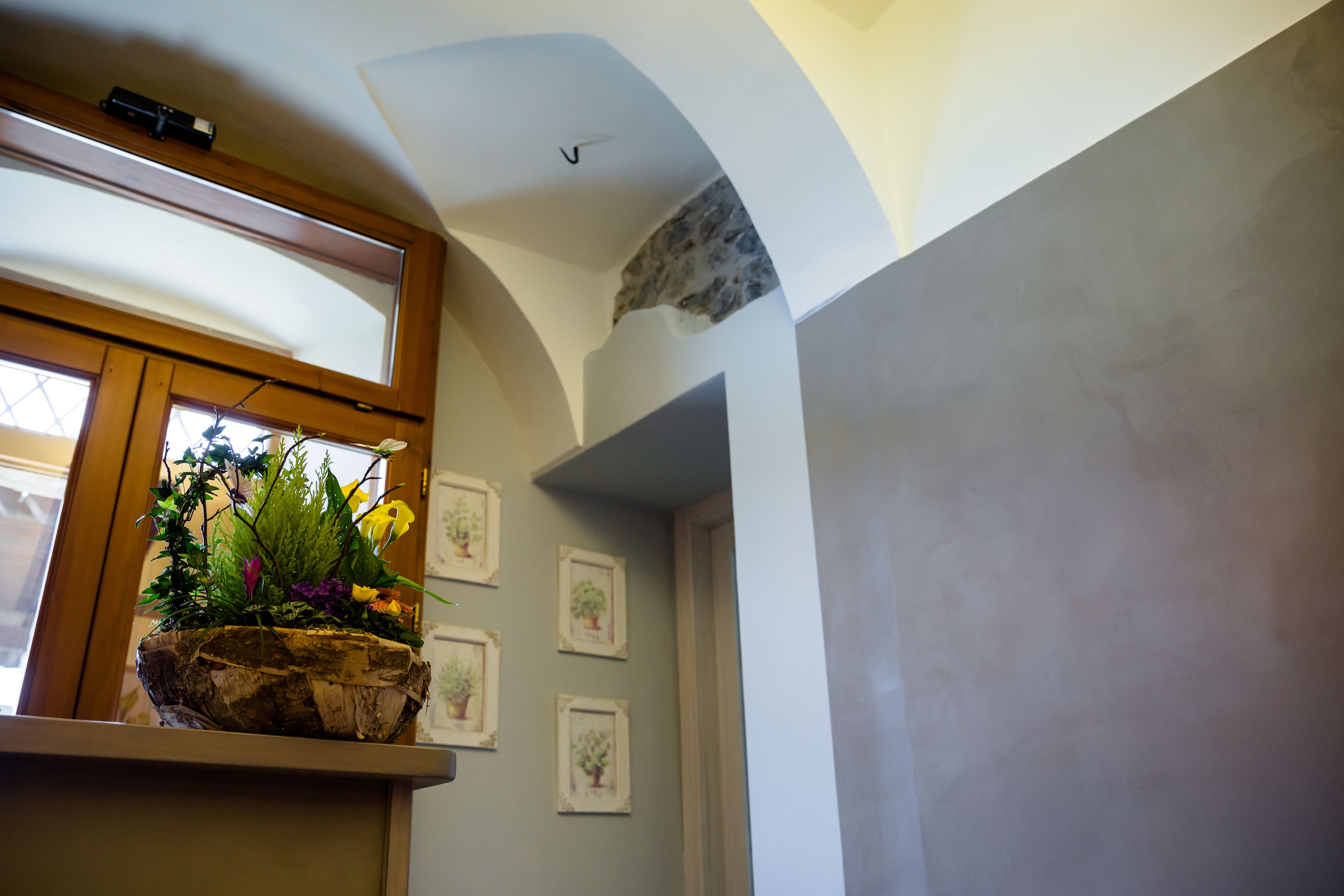 Ein Zimmer mit Fenster, einer Holzablage mit Pflanze und gerahmten Bildern an der Wand.
