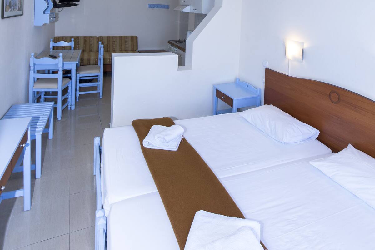 A hotel room with two beds, a desk, and a chair. There is a staircase leading to an upper level.