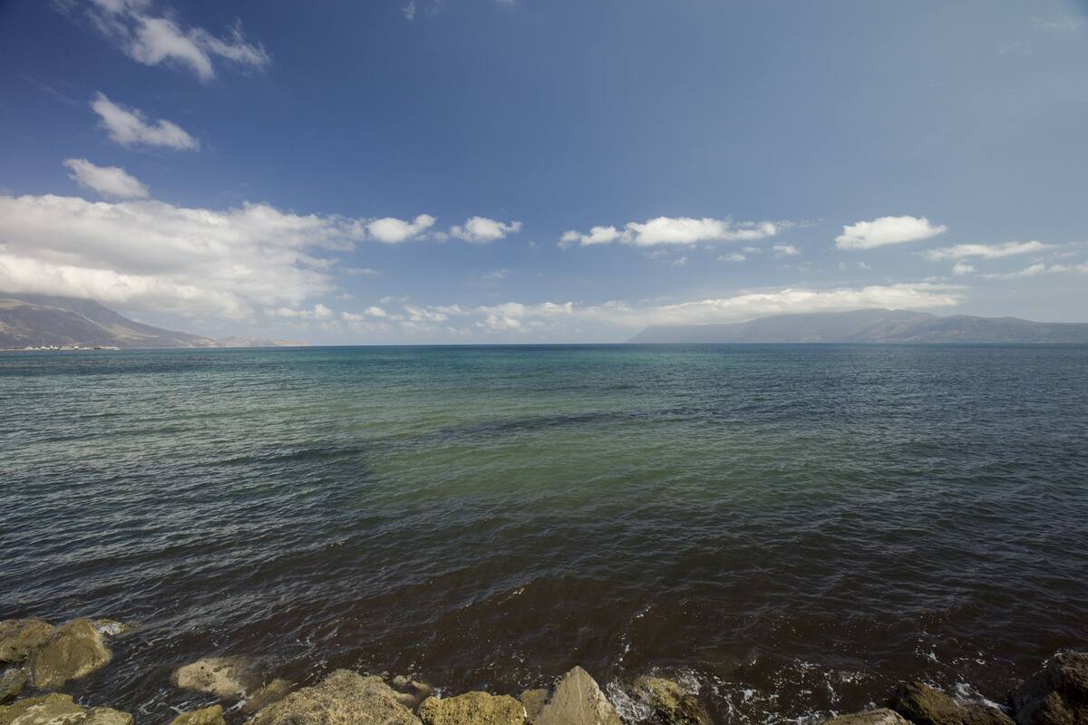 A coastal landscape with a rocky shoreline and calm sea.