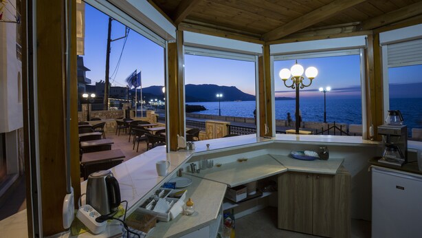 A cozy bar area with a view of the sea and mountains at dusk. - Mandy Suites (Kissamos)