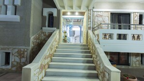 A staircase with stone walls and a white railing leading to a second-floor balcony with a railing. - Mandy Suites (Kissamos)
