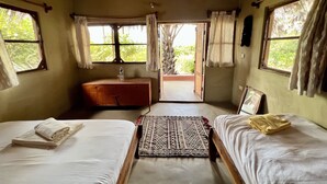 Una habitación con dos camas, un armario de madera, un ventanal con cortinas y vistas al exterior.
