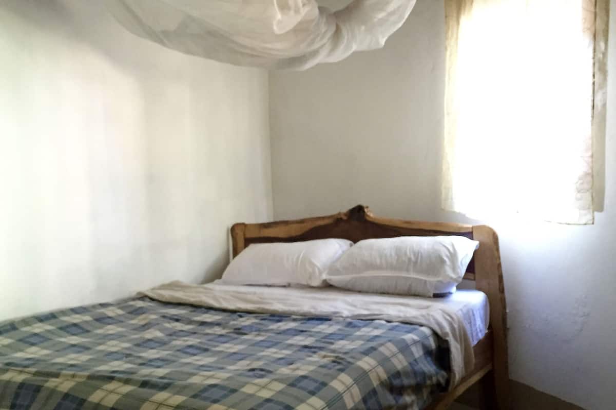 A single bed with a checkered bedspread, a wooden headboard, and white pillows.