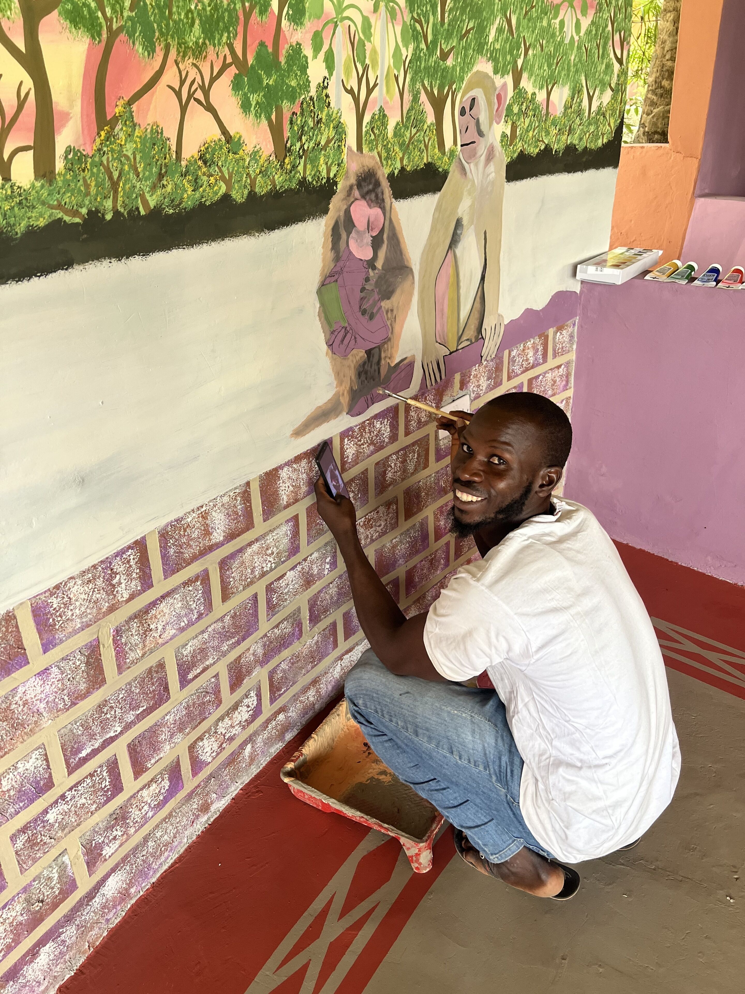 Un uomo dipinge un murale su un muro di mattoni.