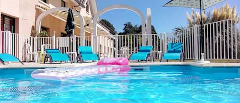 Una piscina al aire libre, sillones reclinables de piscina